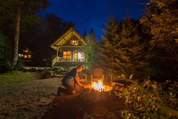 Homme qui fait un feu près du Chalet nature au parc national du Mont-Tremblant