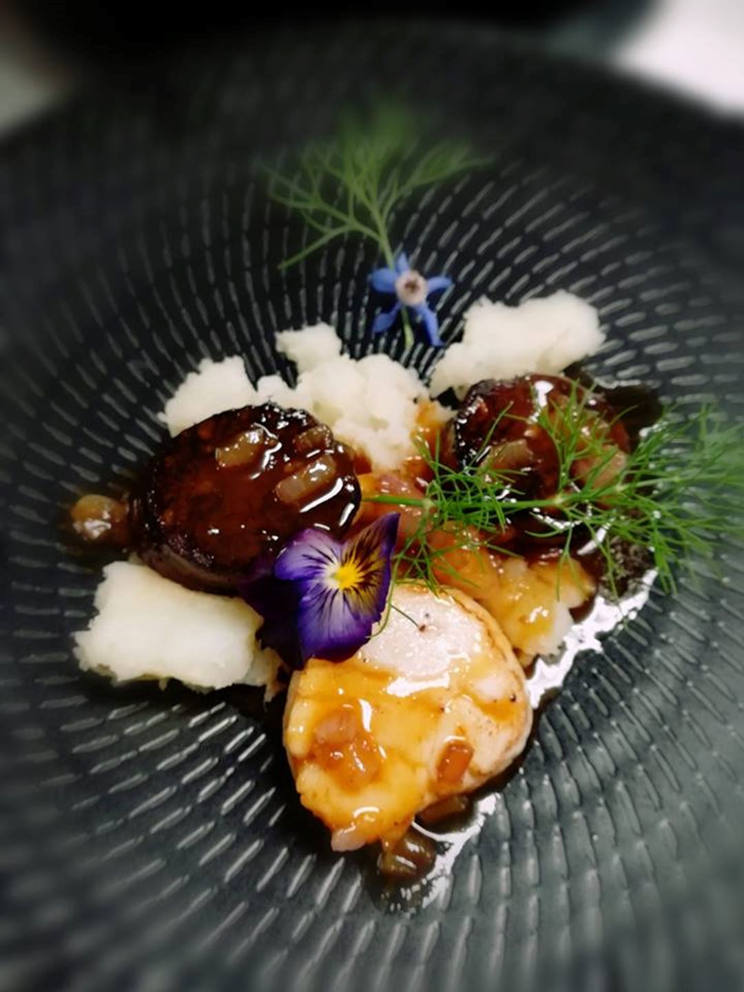 Service de viande et riz dans un bol noir accompagné d'une petite fleur.