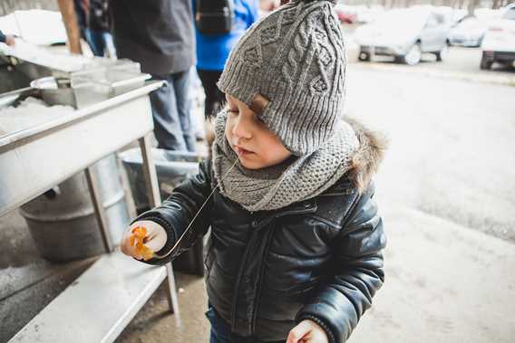 Little boy eating maple taffee at maple grove L'aKabane
