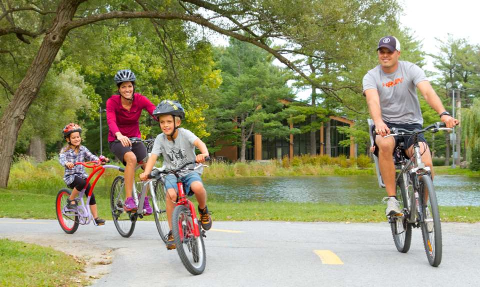A happy family ride a bicycle in the Parc du Grand-Coteau