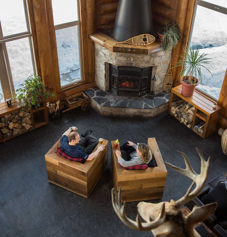 Couple qui relaxe devant un foyer dans l'Auberge du Lac Taureau