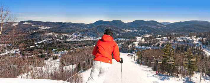 Man skiing on top of a mountain with the view of all the mountains during winter