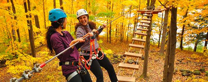 Deux filles dans les parcours dans les arbres à Arbraska en automne