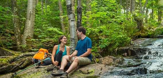 Couple prenant un pause près d'un ruisseau 